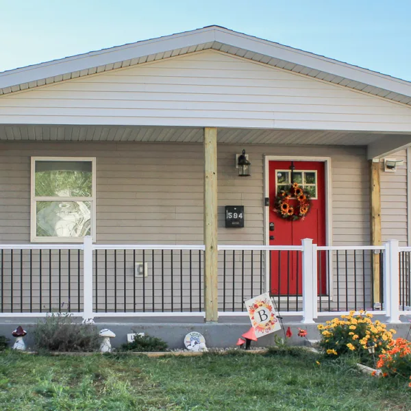A single family one story home featuring a newly built front porch with wood railing and steps, showcasing custom porch construction in detail.